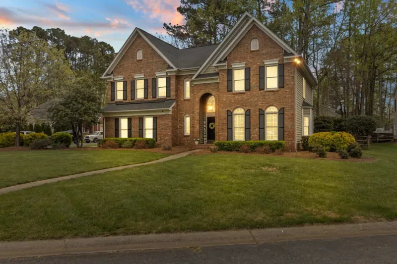Brick colonial at twilight with lit windows