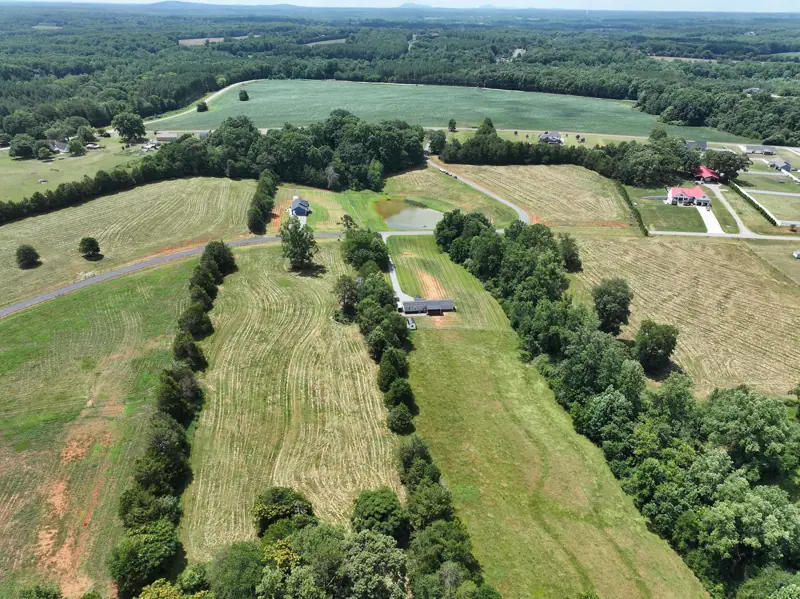 Wide drone view over rolling farmland and tree lines