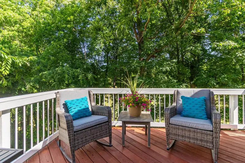 Wood deck with cushioned chairs overlooking trees