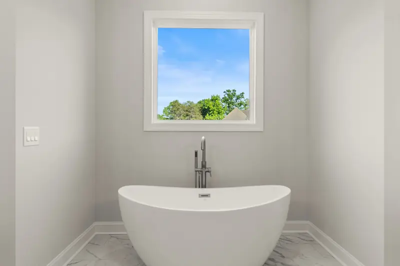 Freestanding soaking tub beneath a window