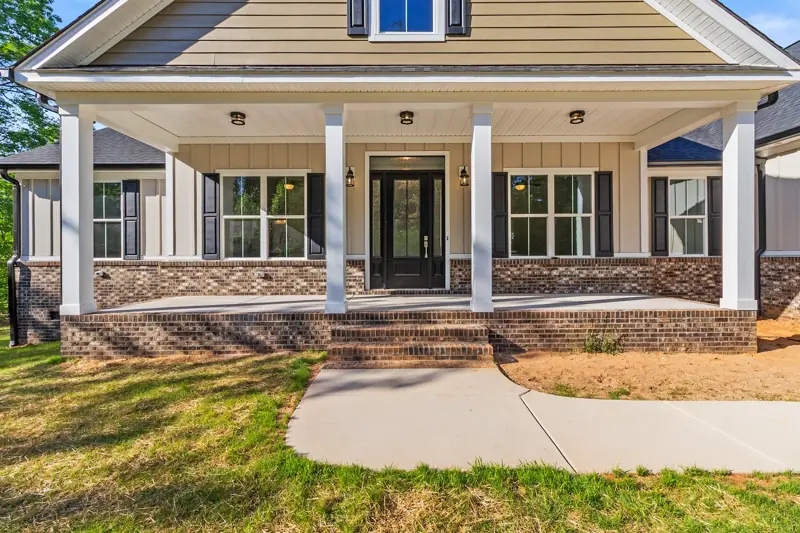 Covered front porch with white columns on a new brick home
