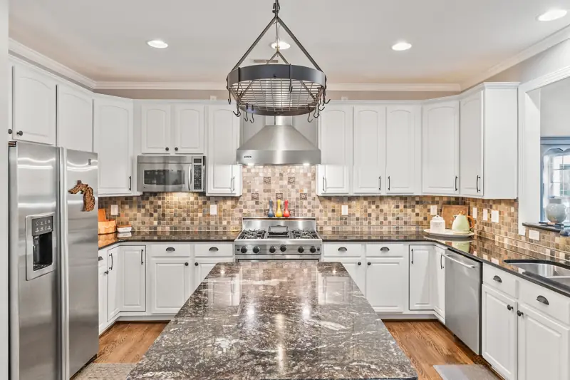 White kitchen with granite island and stone backsplash