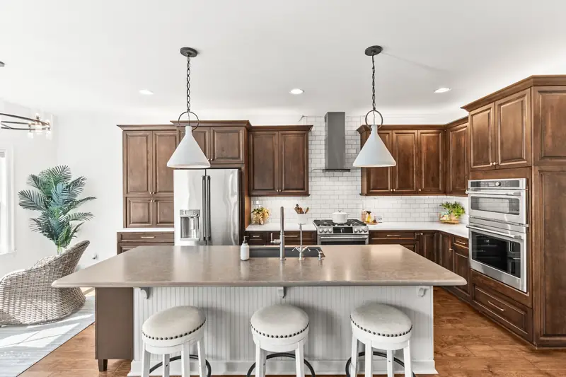 Kitchen with rich wood cabinets, island seating and pendant lights