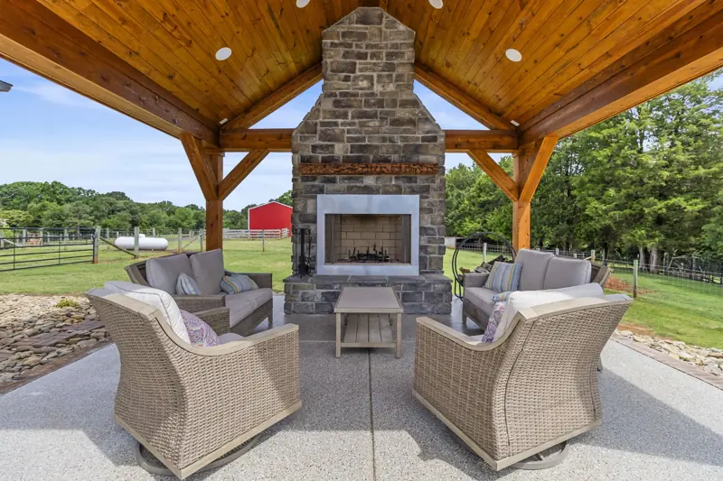 Covered outdoor living room with stone fireplace and wicker chairs