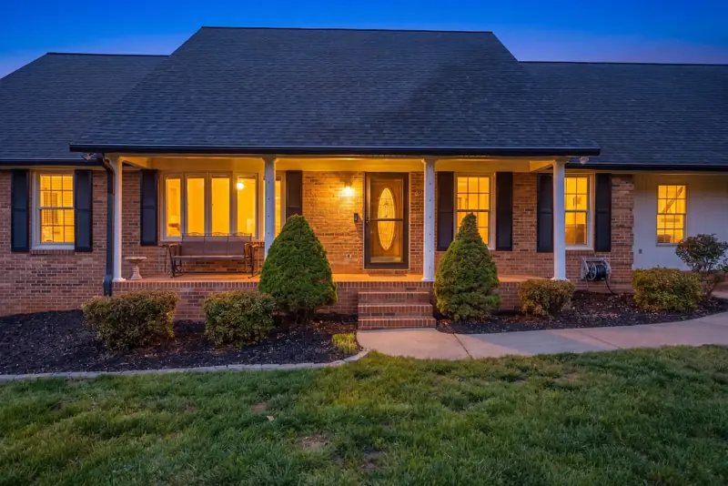 Brick ranch home with a glowing front porch at twilight