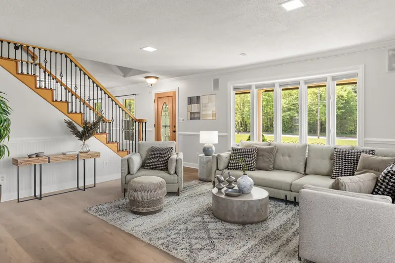 Virtually staged living room with open staircase and large windows